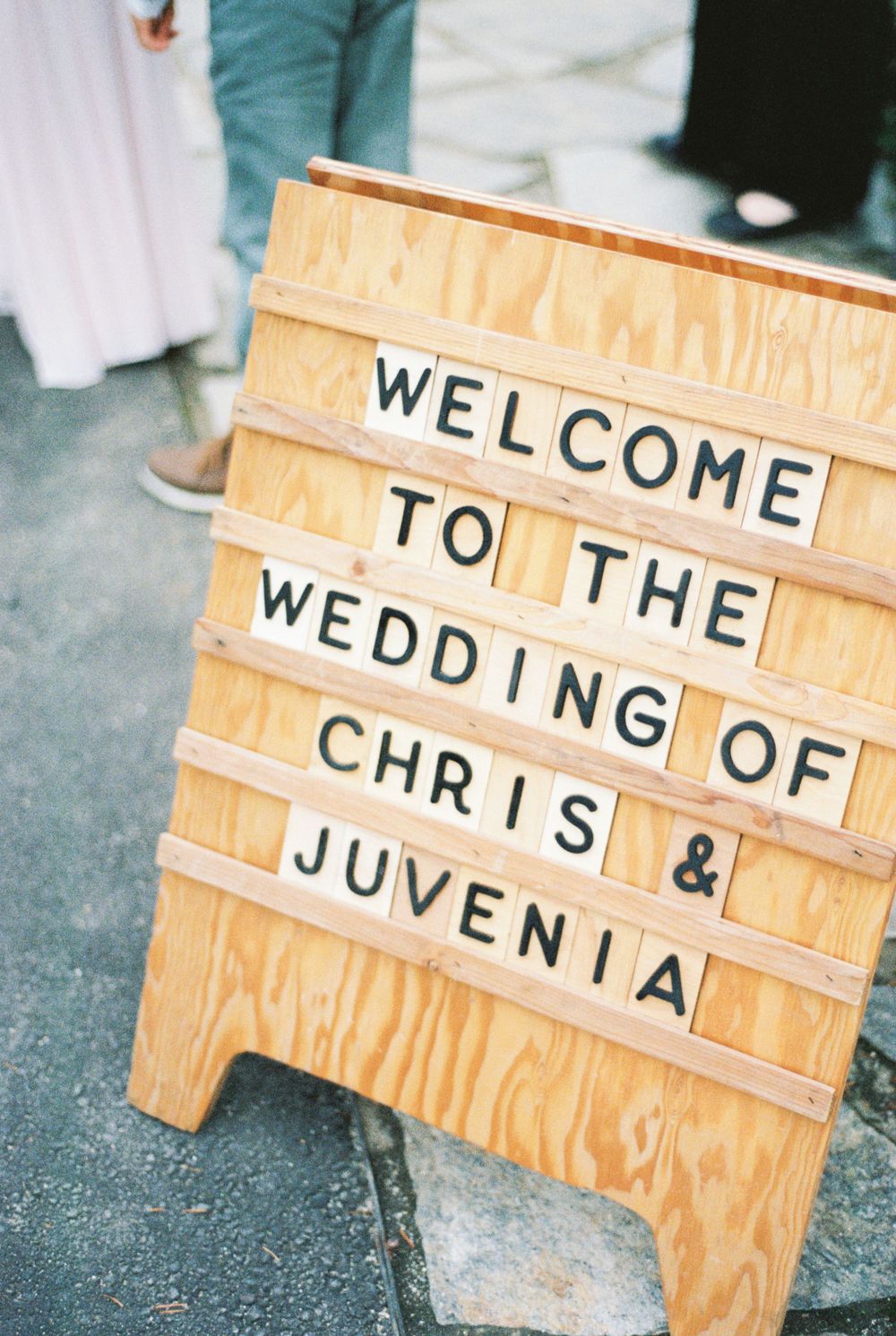 A wooden welcome sign board with letterboard text announcing a wedding.