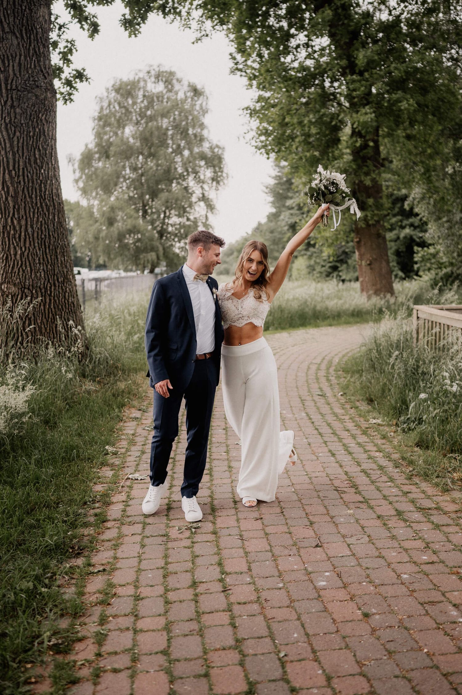 A couple walking together on a brick path through a green park on an overcast day.