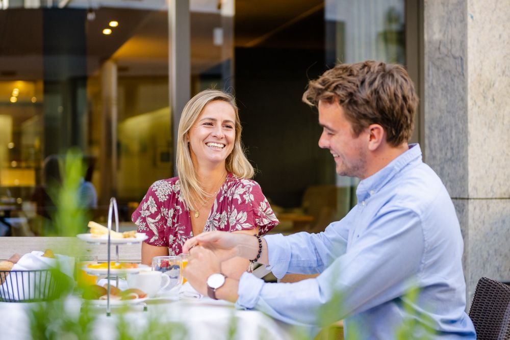 A couple sharing a lighthearted moment during an outdoor meal.