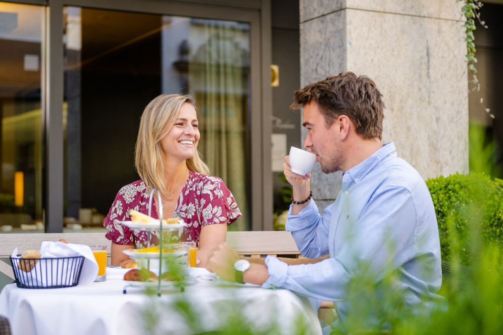 Two people enjoying coffee and conversation at an outdoor cafe.