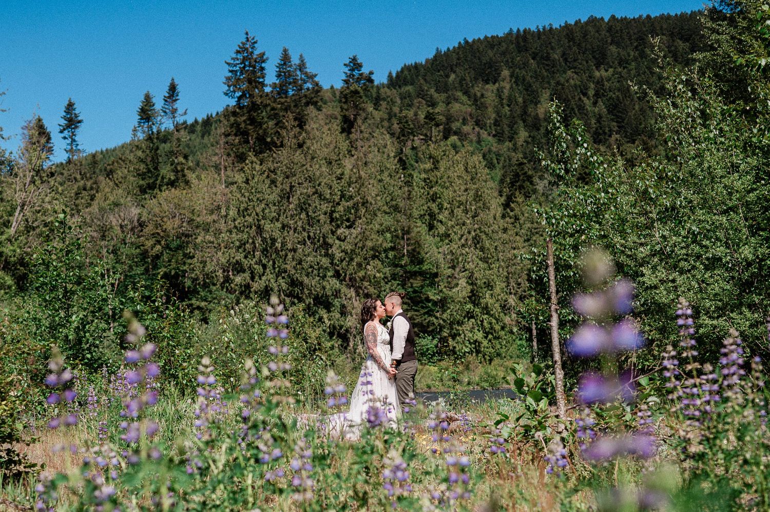 two brides kissing in field of wild flowers