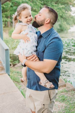 A sweet moment captured between parent and child outdoors near a lake.