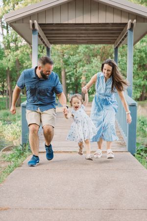 A family enjoying a playful moment running together under a covered walkway.