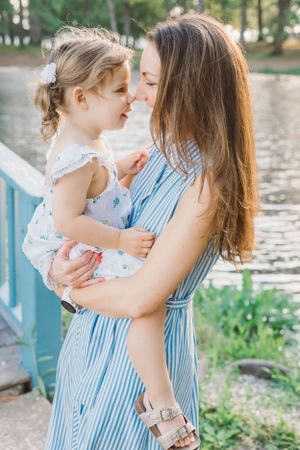 A tender moment shared between parent and child on a bridge near water.