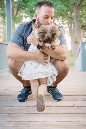 A touching embrace between parent and child on a wooden deck outdoors.