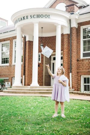 The School entrance features white columns and brick architecture with someone celebrating.
