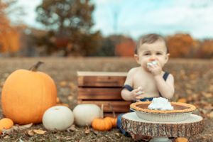 Messy face enjoying dessert outdoors among pumpkins.