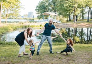 Family playing and having fun together by a pond on a sunny day.
