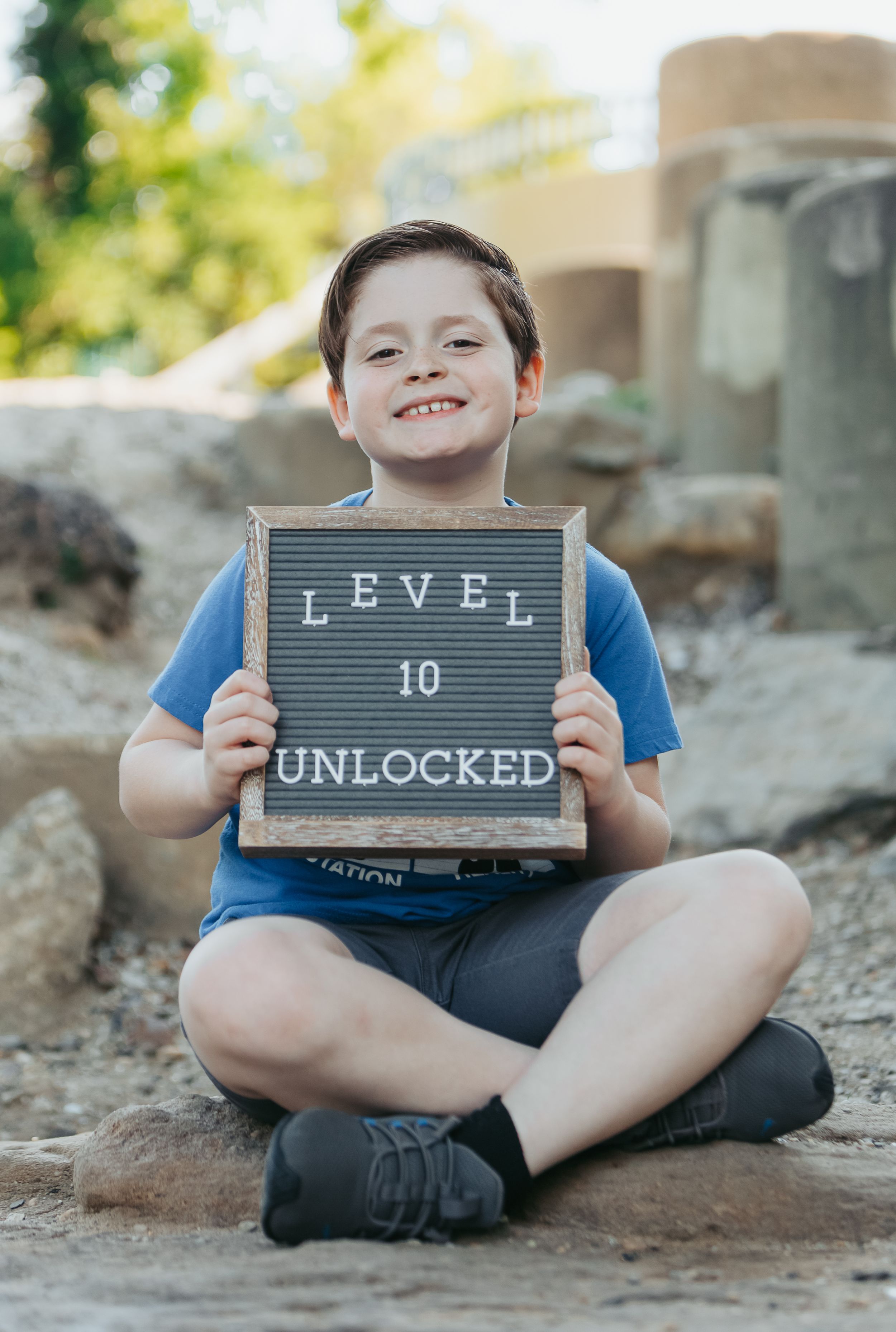Child sitting cross-legged holding letterboard saying Level 10 Unlocked.