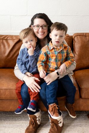 Family portrait on brown leather couch in casual clothing.