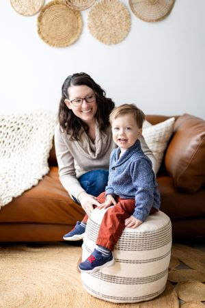 A cozy living room scene with two people sitting on a brown leather couch under decorative woven wall baskets.