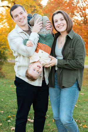 A family enjoying an autumn day outdoors with golden fall foliage in the background.