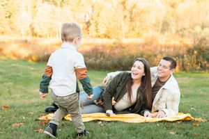 Family enjoying golden autumn sunset while relaxing together on picnic blanket outdoors in nature.