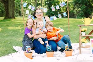 People enjoying outdoor tea party and gardening activities at a picturesque summer gathering with decorative flags.