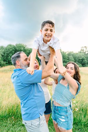 People enjoying a fun moment together in a sunny field with bright blue sky and green grass.