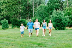 A group walking together through a lush green park or lawn area on a sunny summer day.
