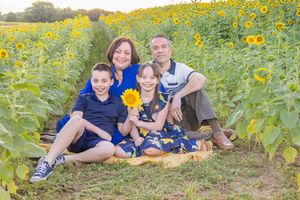 A group sits in a vibrant sunflower field during a summer photo session surrounded by bright yellow blooms.
