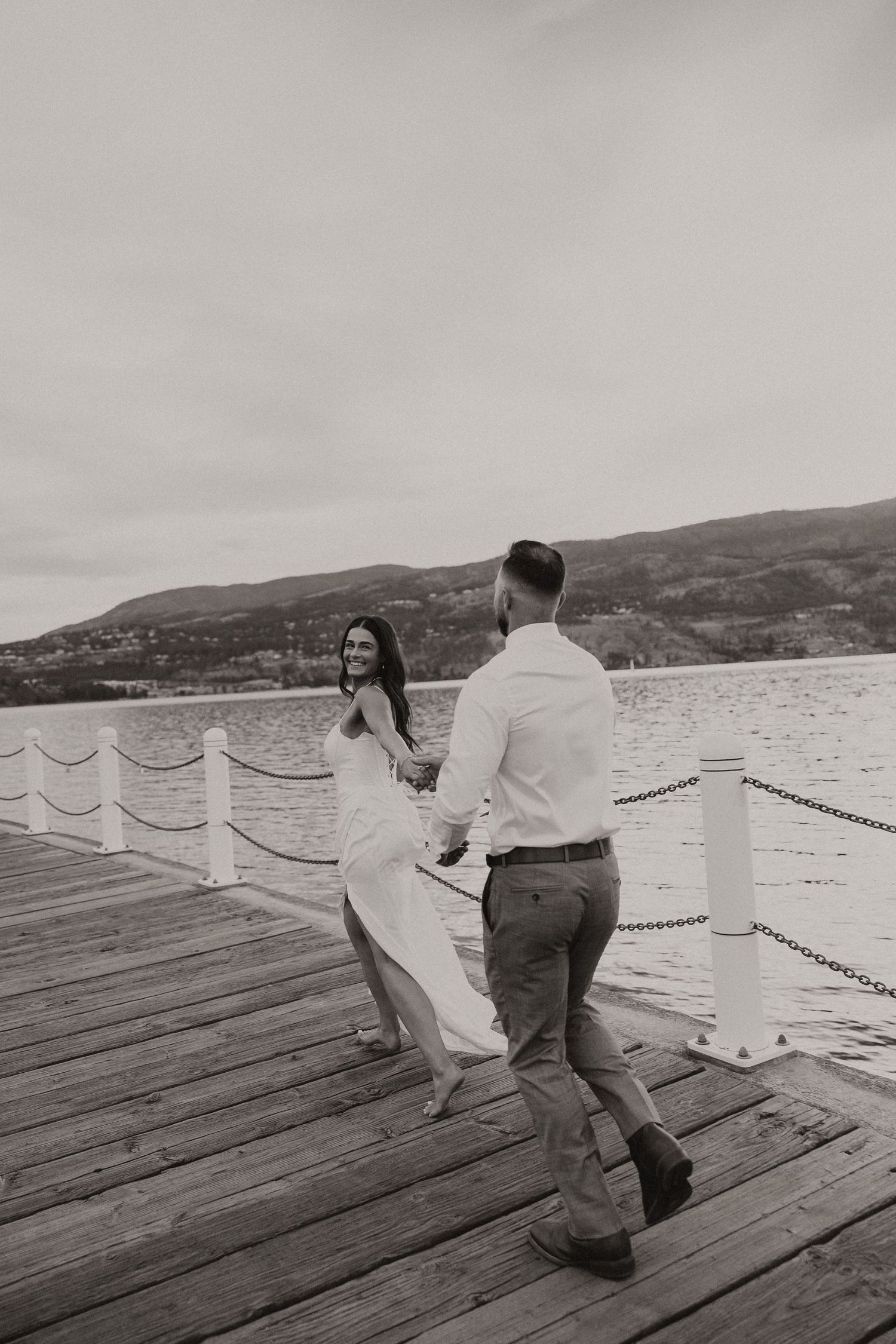 Bride and groom sharing a romantic moment on a wooden boardwalk next to a vintage lamp post.
