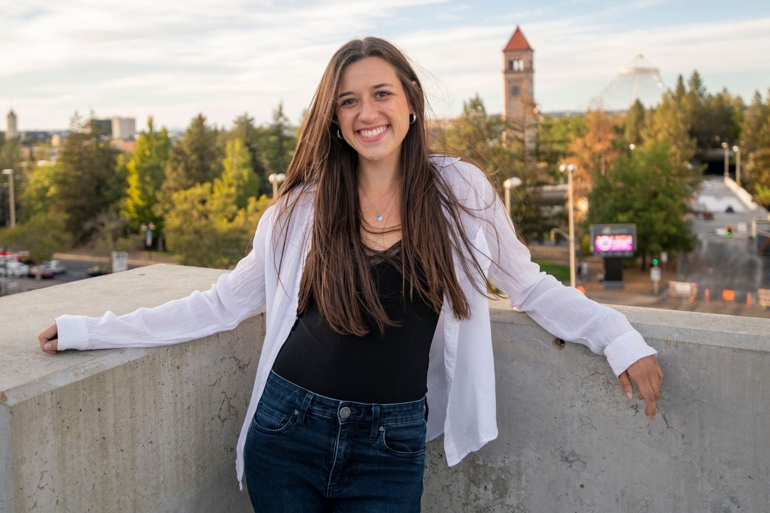 GIRL STANDING WITH BACK TO RIVERFRONT PARK IN DOWNTOWN SPOKANE, SPOKANE SENIOR PORTRAITS