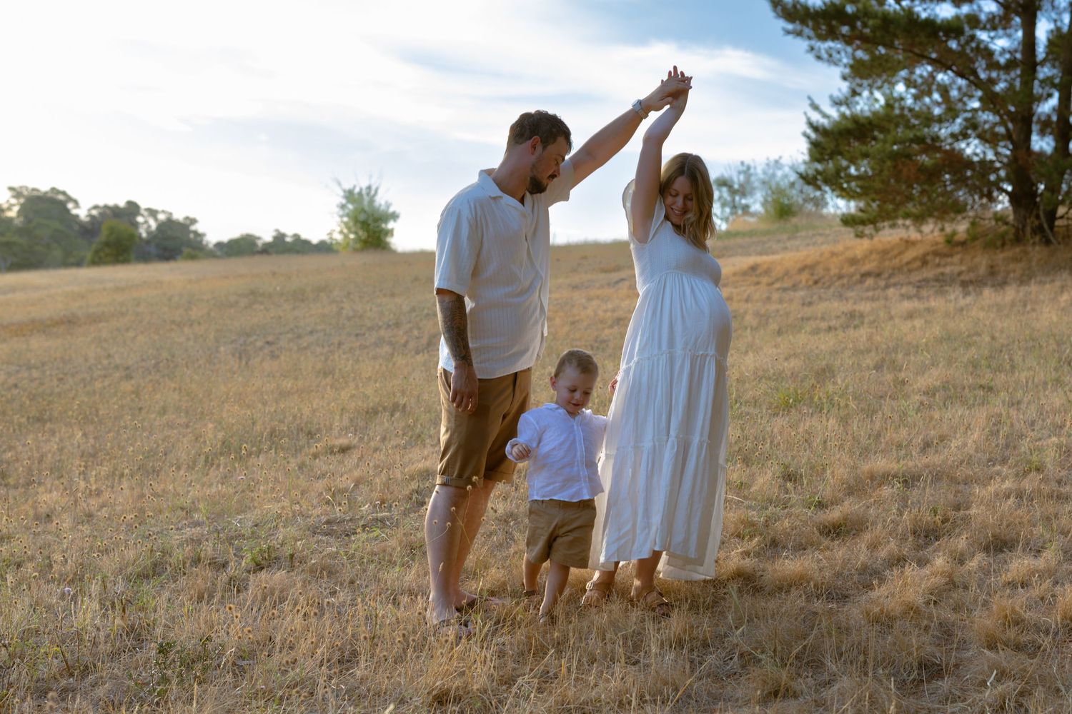 Couple walking together through a sun-drenched meadow at golden hour, holding hands in a romantic embrace.