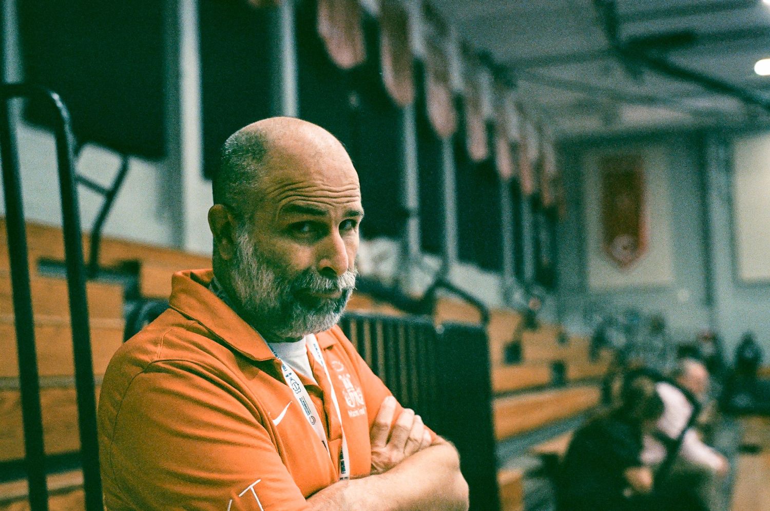 Man in orange shirt photographed in what appears to be an auditorium or theater setting.