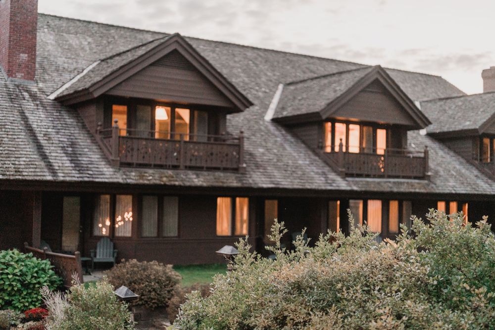 Rustic wood lodge with dormer windows glowing warmly at dusk at Trapp Family Lodge, a wedding venue in Stowe, Vermont