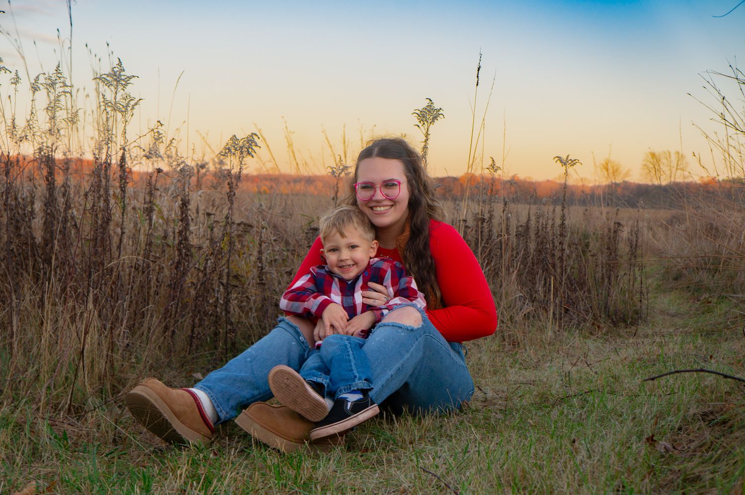 Outdoor sunset portrait in field with tall grass and warm lighting.