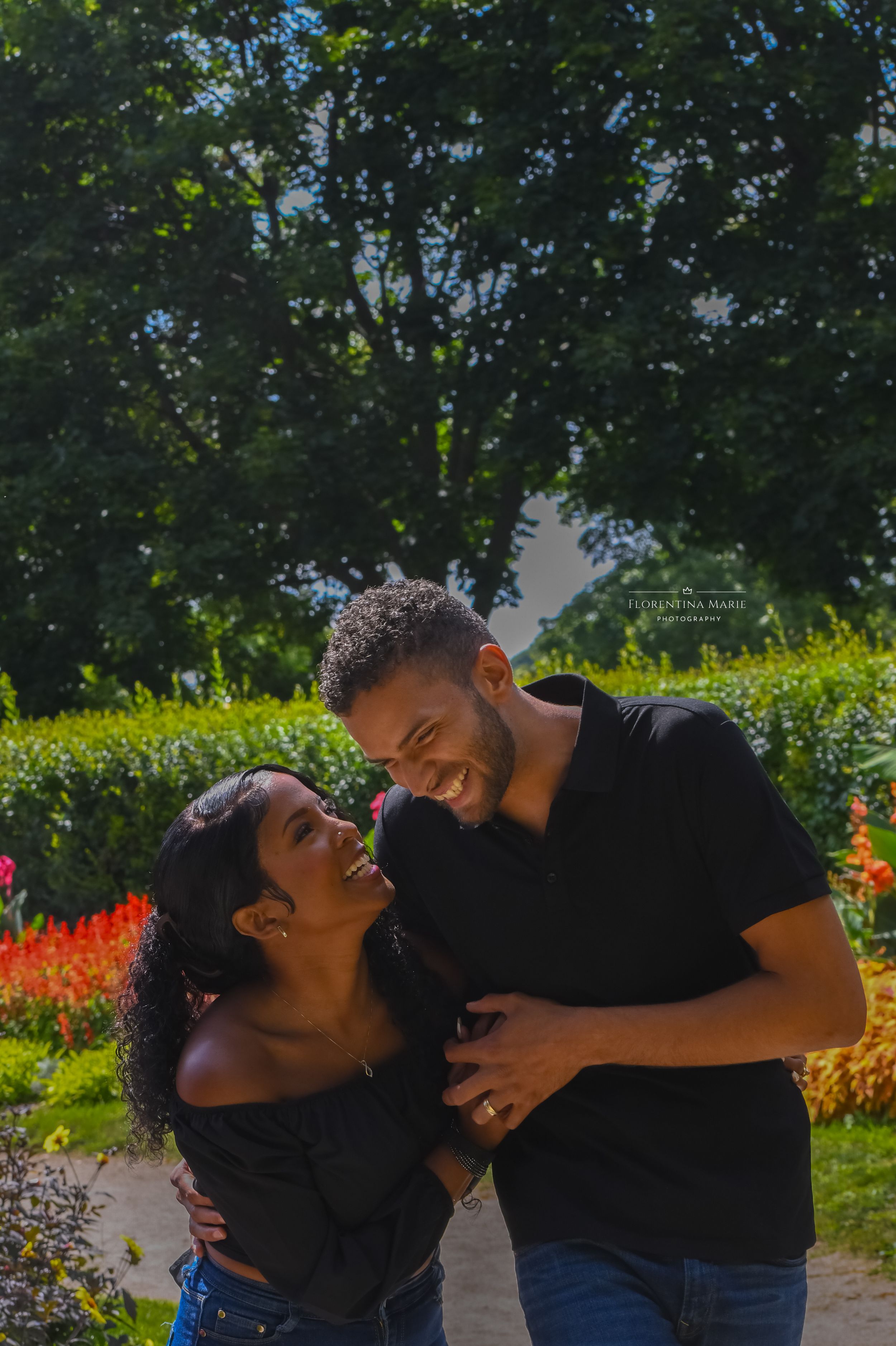 Happy couple sharing a joyful moment together in a garden setting with bright flowers and greenery.