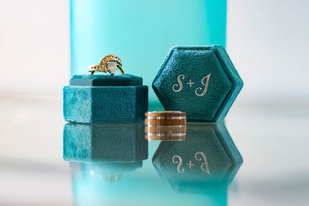 Turquoise hexagonal ring box with wedding rings and monogram details.