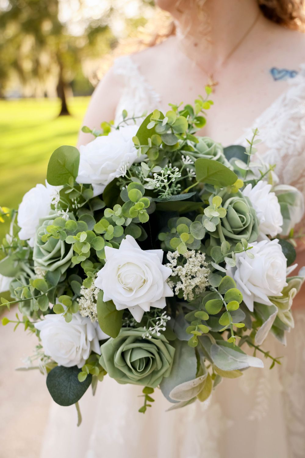 Elegant bridal bouquet featuring white roses and sage green foliage.