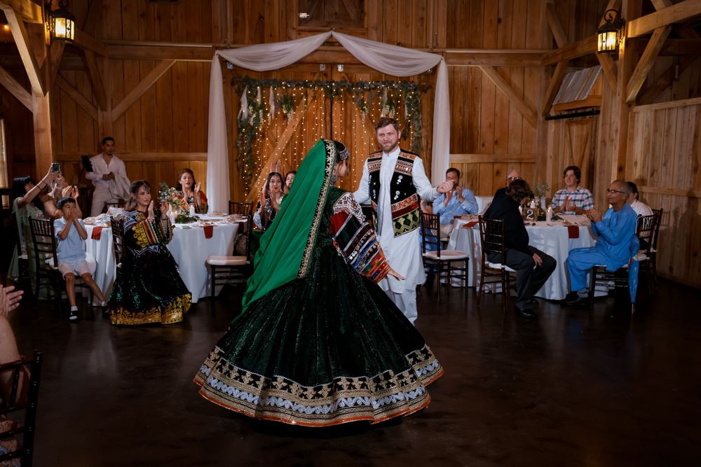 Wedding reception in rustic barn venue with traditional Afghan cultural dress and decorations.