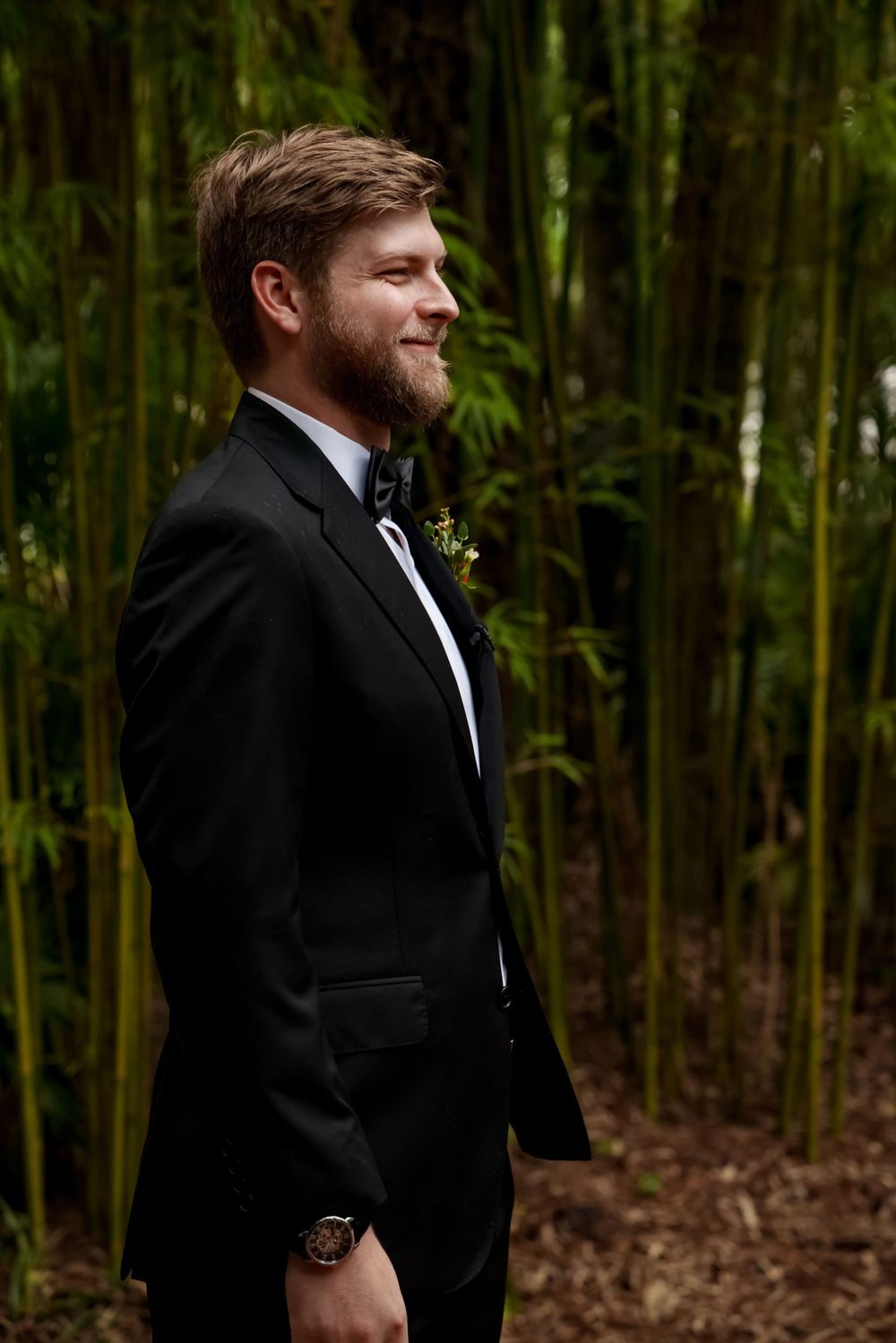 Formal black tuxedo against bamboo forest background.