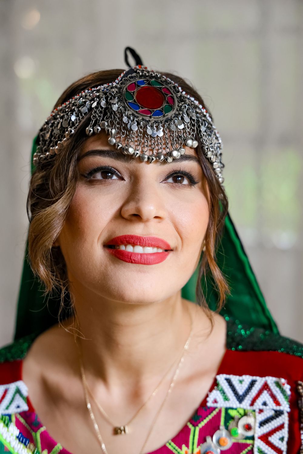 Traditional ornate silver headpiece with jewels and green veil in ethnic style.