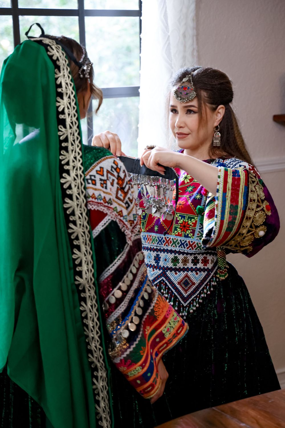 Colorful traditional Afghan dress with intricate embroidery patterns and green veil details.