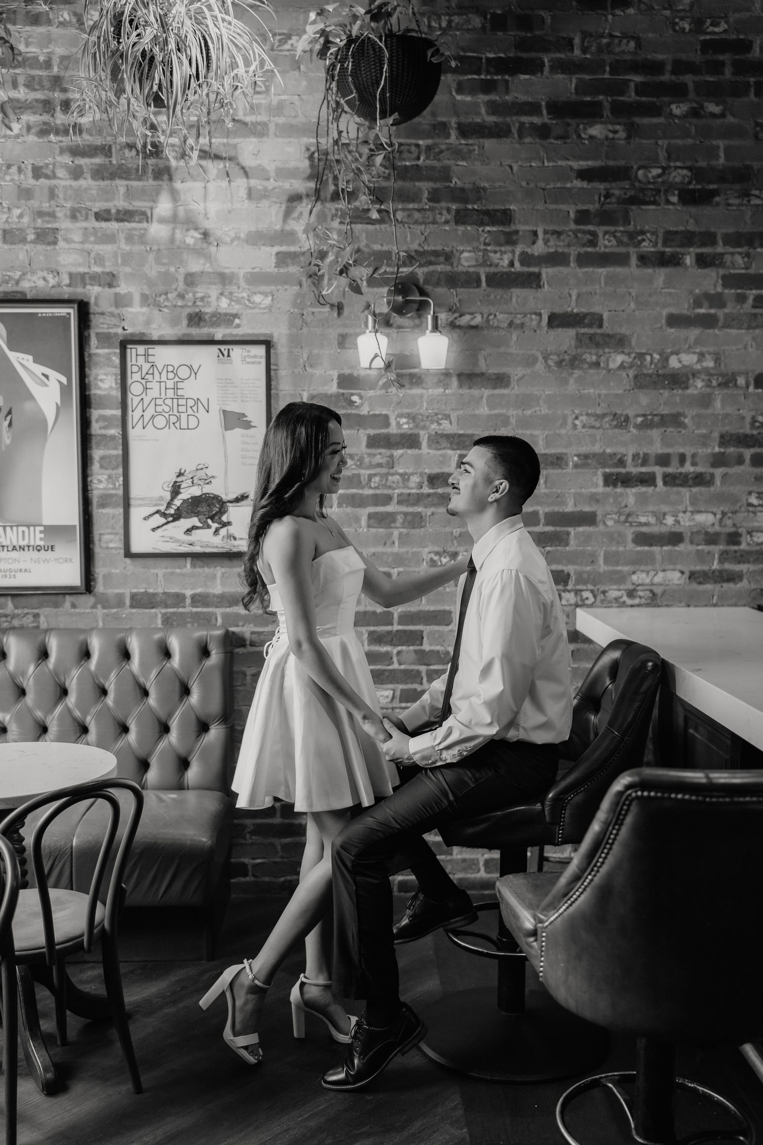 A romantic couple shares an intimate moment in a vintage-style restaurant with exposed brick walls and industrial lighting.