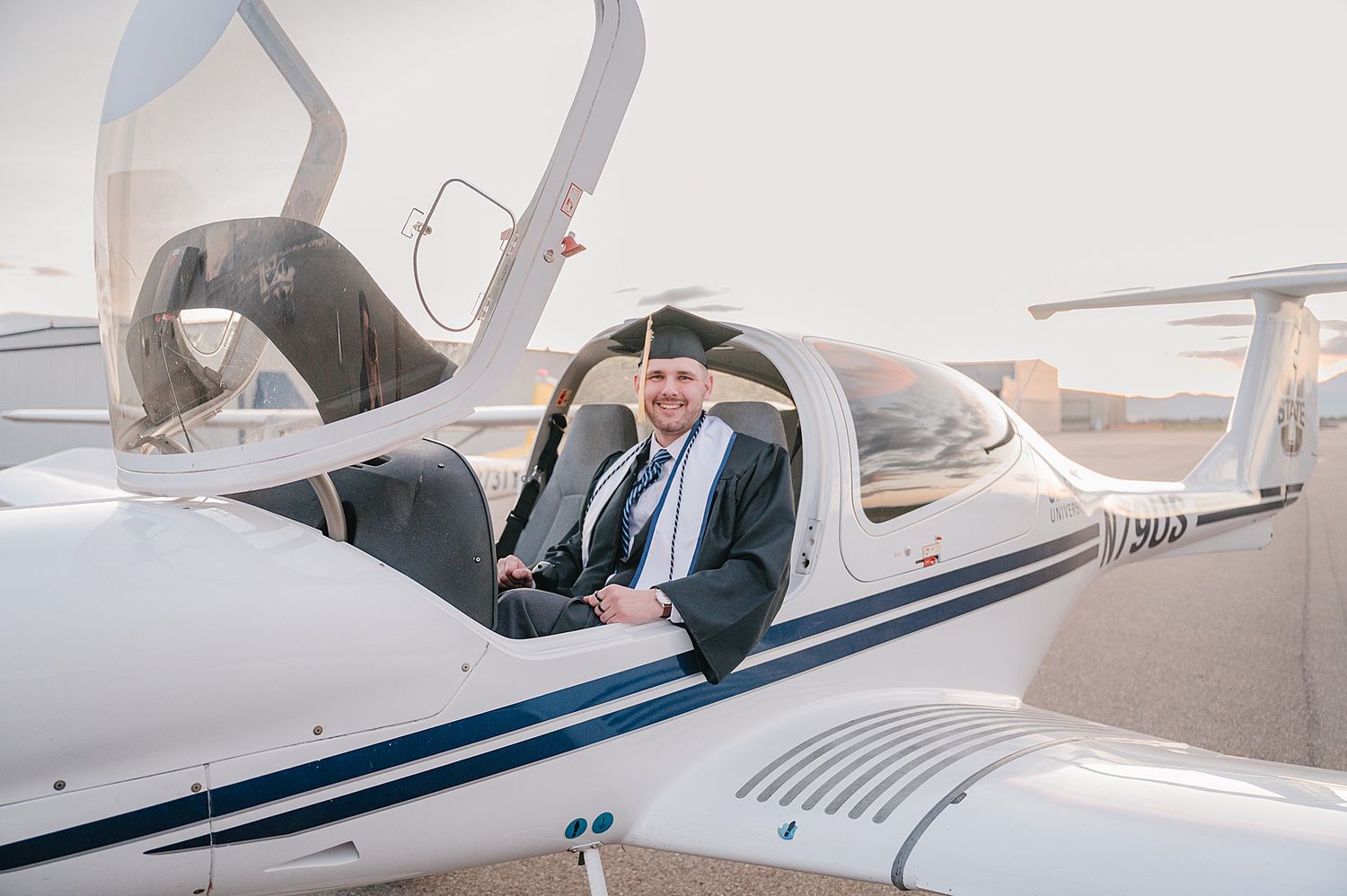 Two-seater private aircraft at an airfield with someone sitting in the cockpit wearing business formal attire.