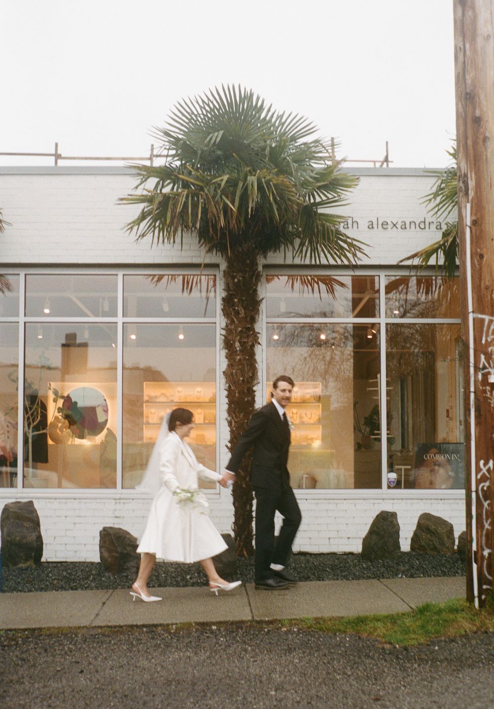 Storefront view with palm trees and white exterior walls.