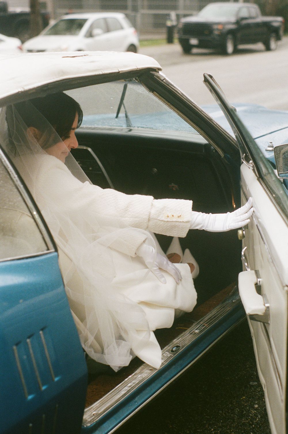 Sequence of someone in a white dress entering a classic blue car.