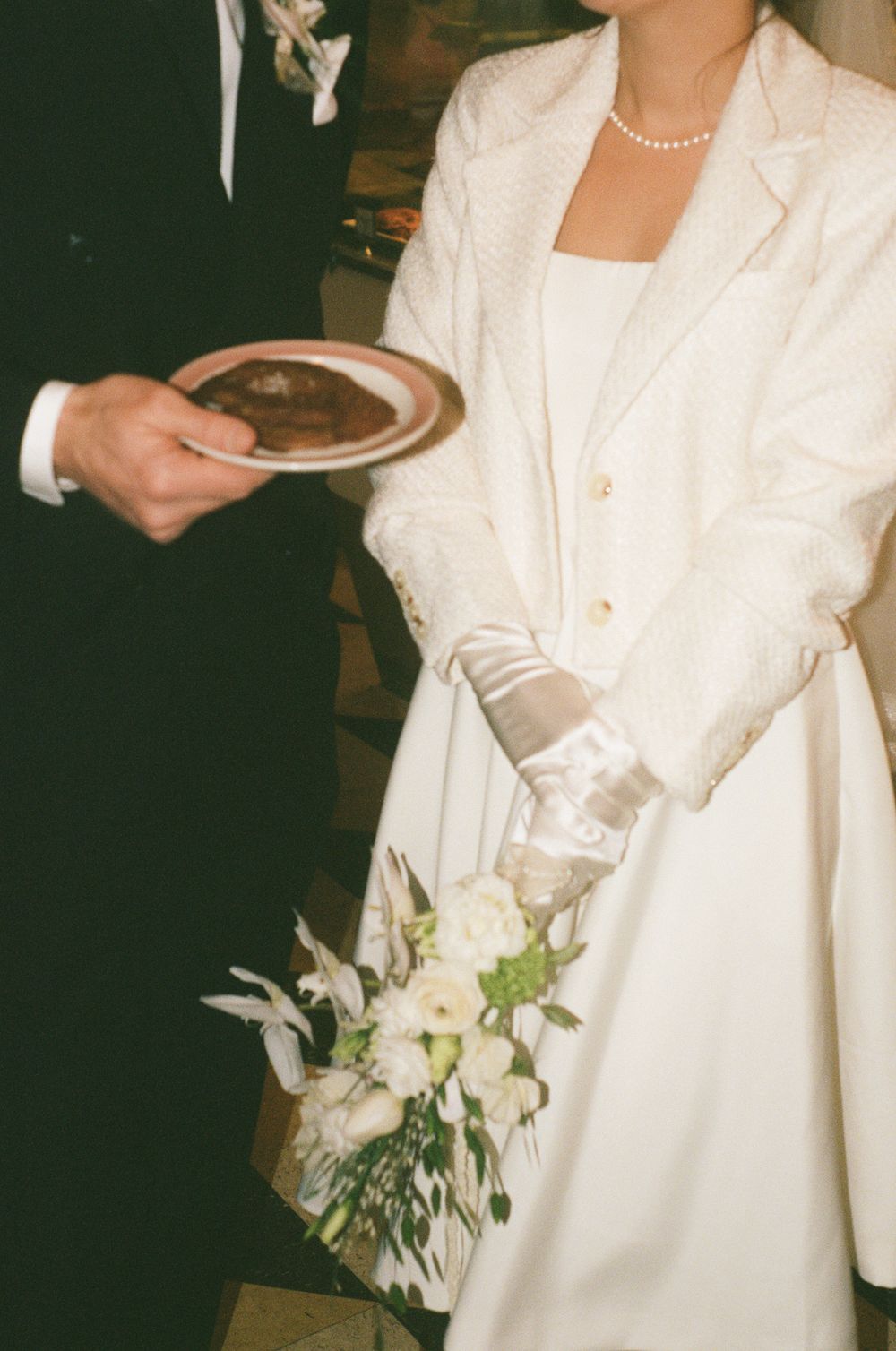 Elegant white bridal attire with delicate pearl necklace and white floral bouquet details.