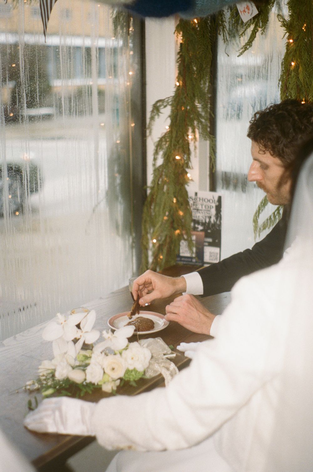 Wedding table setting with white floral arrangements and place settings at an indoor venue.