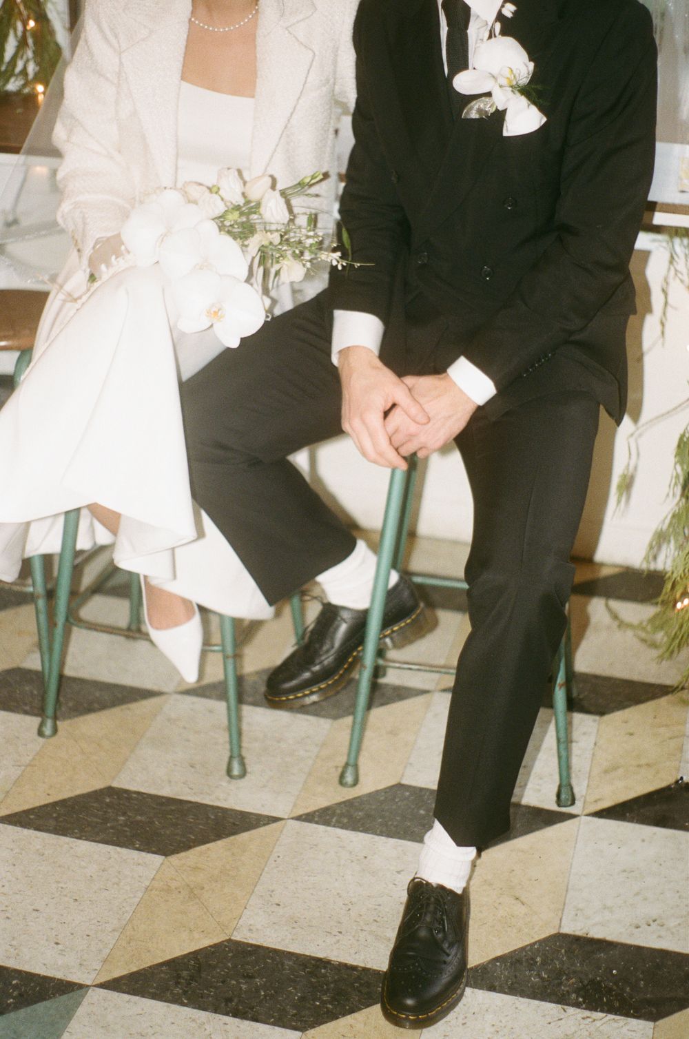 Formal black and white attire detail shot showing dress shoes and hemlines at a wedding.
