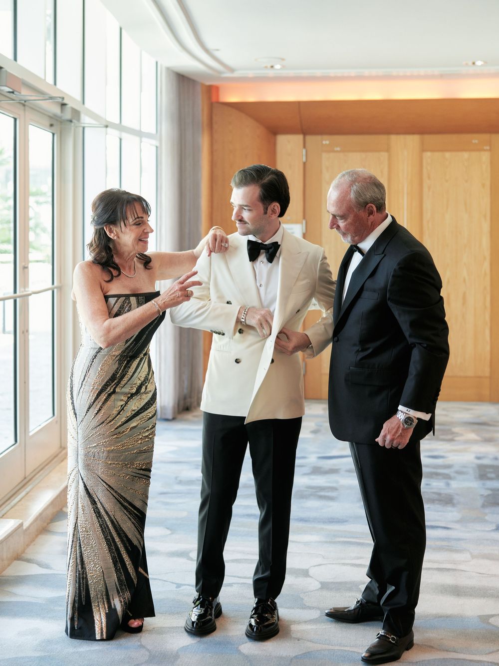 Wedding celebration candid moment in an elegant hotel hallway with large windows.