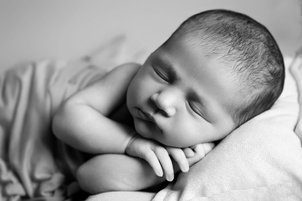 Black and white portrait of sleeping newborn with soft lighting.