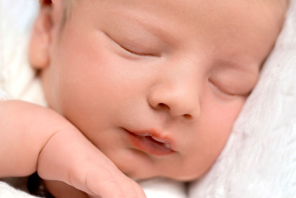 Serene close-up of sleeping newborn with rosy skin tones.