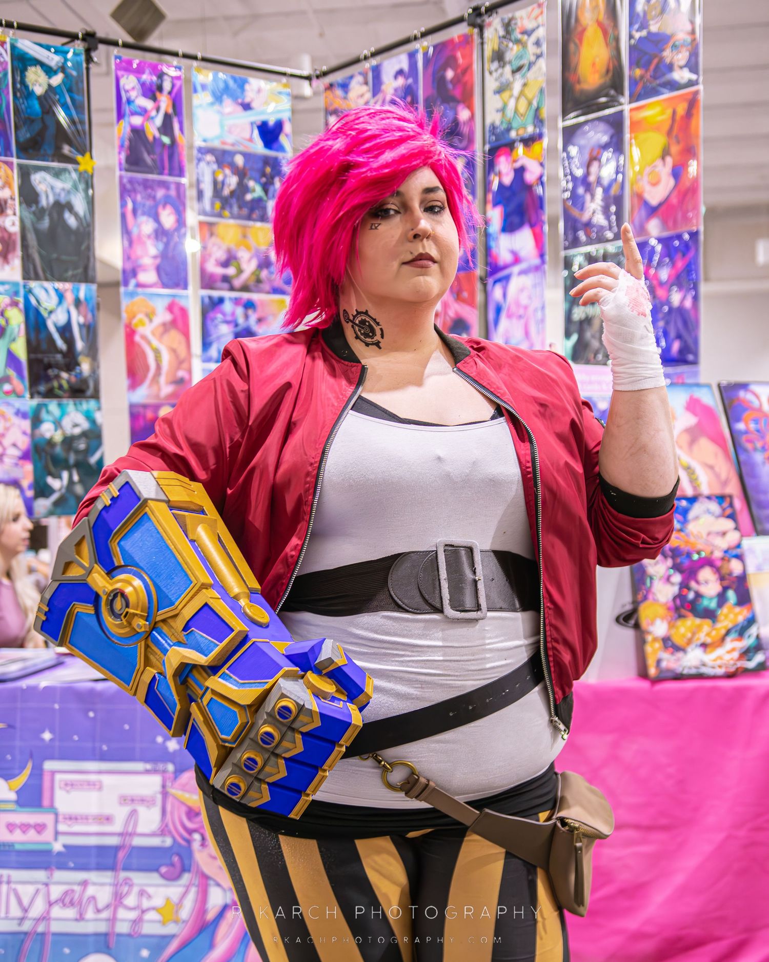 Cosplayer with bright pink hair wearing a red jacket and steampunk-style accessories.