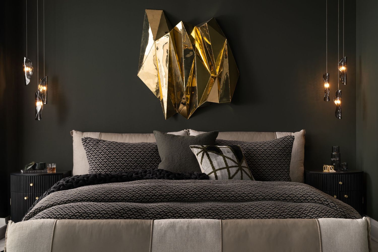 Modern dark bedroom with gold wall art decor, quilted bedding, and contemporary pendant lighting against charcoal walls.