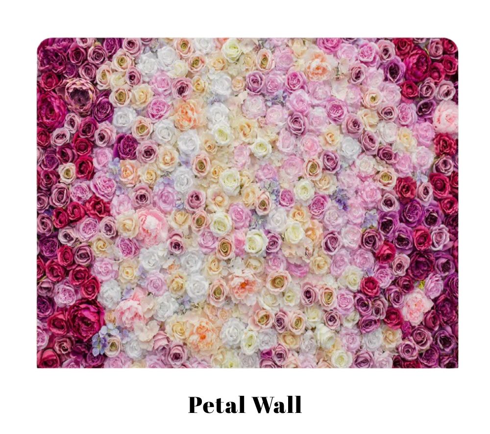 A decorative floral wall backdrop featuring pink, purple, and white roses arranged in an ombre pattern creates a romantic display.