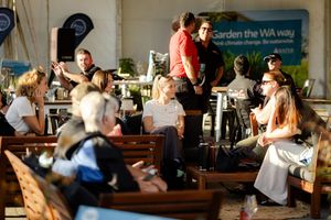 Outdoor live music performance with audience seated on benches enjoying the show.