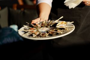 A close-up view of freshly shucked oysters arranged on a dark plate with garnishes.