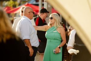 People socializing at an outdoor summer event under a white tent.